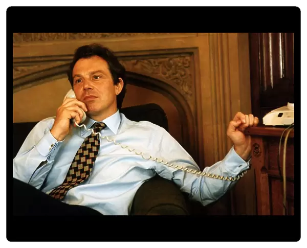 Tony Blair sitting on the sofa holding a telephone handset to his ear