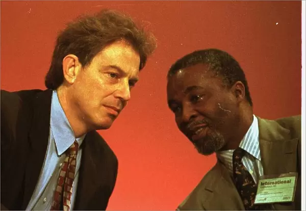 Tony Blair leans over on the platform to talk with Thabo Mebeki of South Africa at