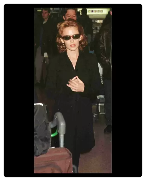 Kylie Minogue leaving Heathrow for Glasgow November 1997 hands clasped black coat