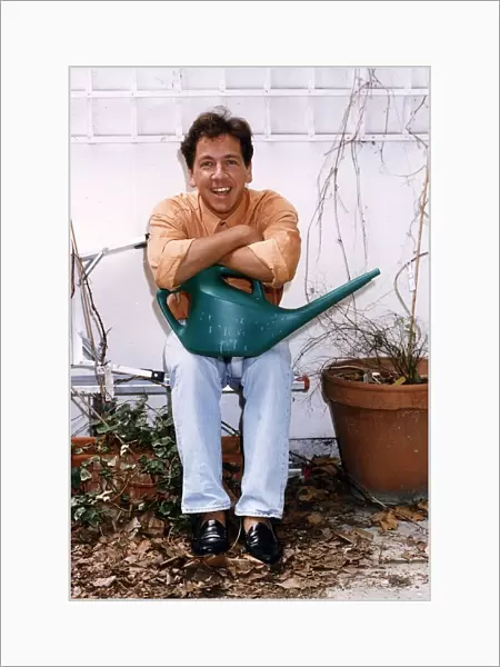 Ross King TV presenter in his garden holding a watering can