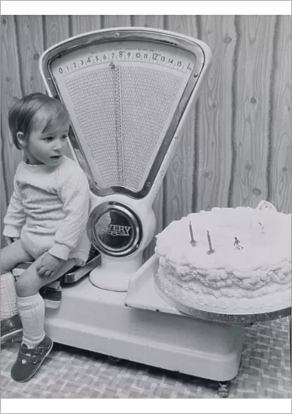 John McLean of West Lothian, Scotland checks his weight against his second birthday cake