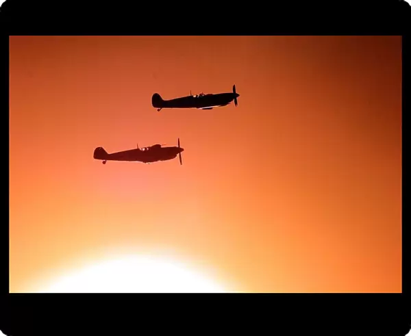 A Spitfire and ME109 (bottom) fly over the war memorial, with a low autumnal sun behind