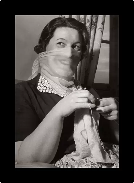 Mrs F Sharpen wearing a veil as she knits at home 1956