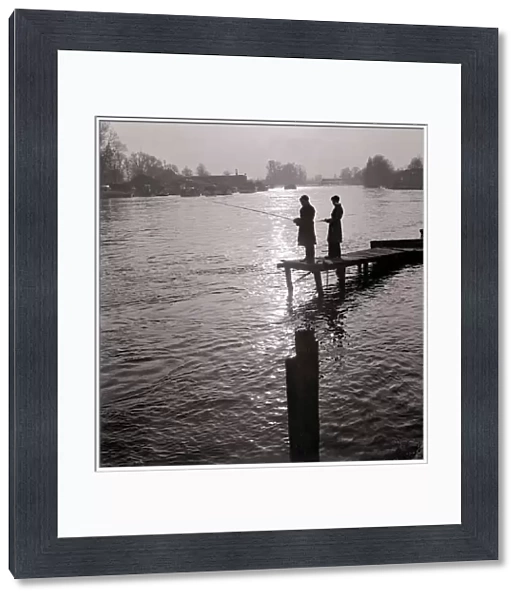 Two young boys fishing as they stand on the end of a jetty, England 1963
