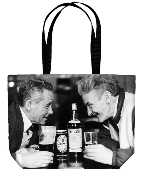 Two old man in pub drinkers bottle of Bells whisky can glass of Guinness facing each