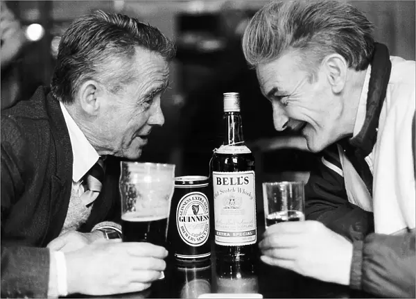 Two old man in pub drinkers bottle of Bells whisky can glass of Guinness facing each