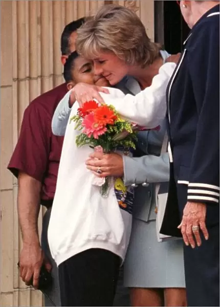 Diana, Princess of Wales, hugs a young girl who gave her flowers as she leaves Cook