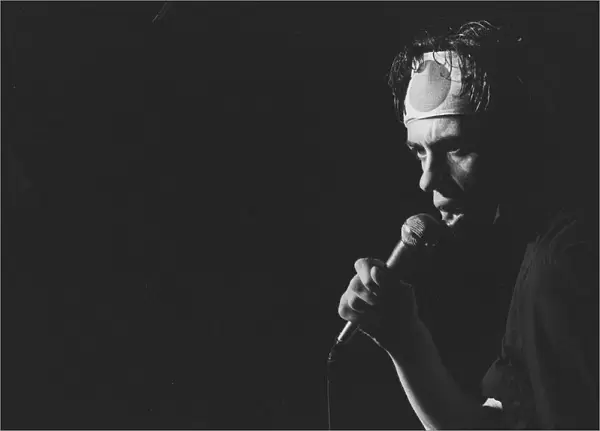 Bob Geldof of the Boomtown Rats pop group, pictured wearing a headband during a concert