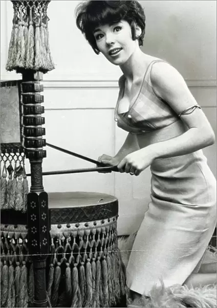 Actress Katy Wild beating an old African drum which is made into a chair