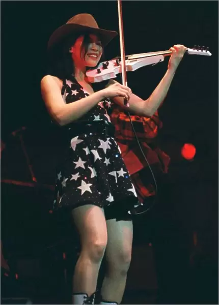 Vanessa Mae on stage playing white violin wearing mini skirt
