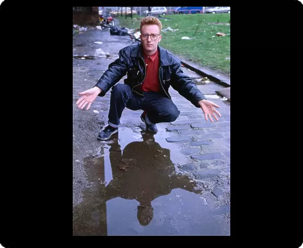 TV presenter Bryan Burnett kneeling next to puddle 1990