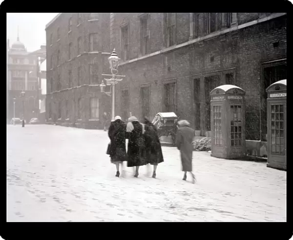 A group of women make their way up the street through the heavy snow past a row of