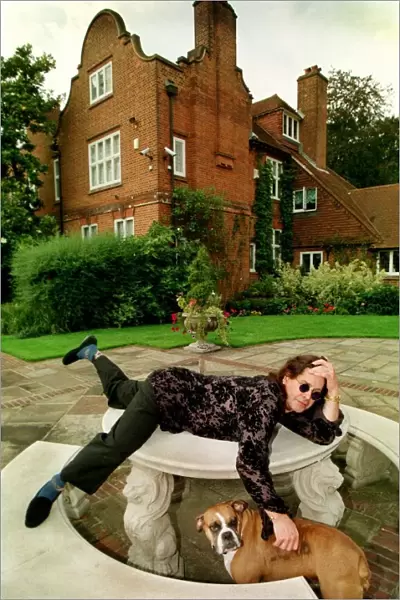 Rock star Ozzy Osbourne at home Lying on a stone table with one of their pet dogs
