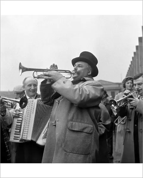 Entertainer Jimmy Edwards wearing a top hat, and his group of buskers entertaining