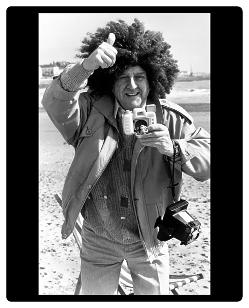 Television comedian Norman Collier wearing a funny wig on the beach April 1991