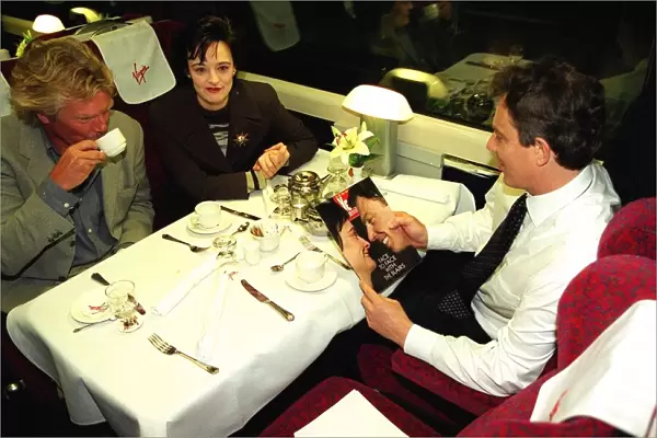 Tony Blair MP reads Yes magazine sitting in dining carriage of train with wife Cherie