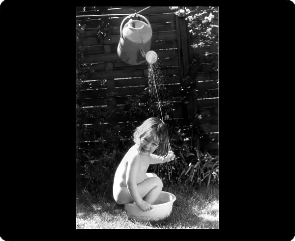Three year old Tom Bardy is enjoying an improvised shower bath in the back garden of his