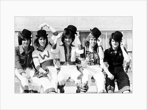 Scottish pop group The Bay City Rollers, sitting on a bench Wearing bowler hats