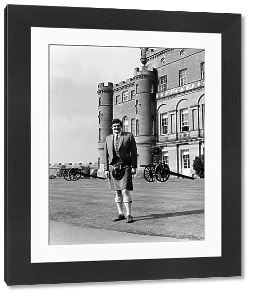Scottish comedian Jimmy Logan standing outside Culzean castle wearing traditional