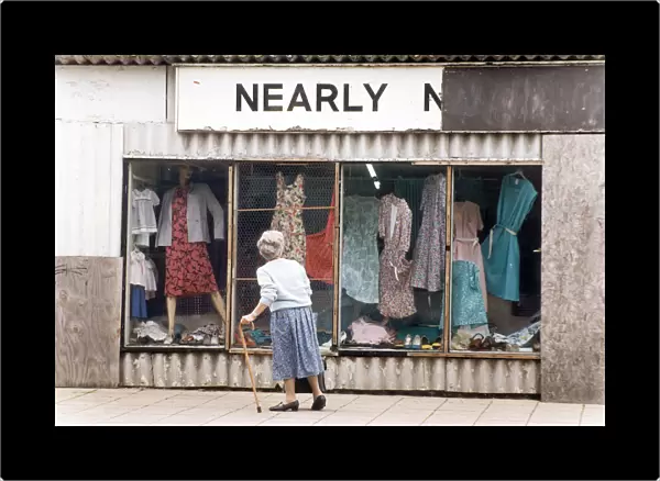 An elderly woman pauses to look at the World War Two prefab shop on the corner of