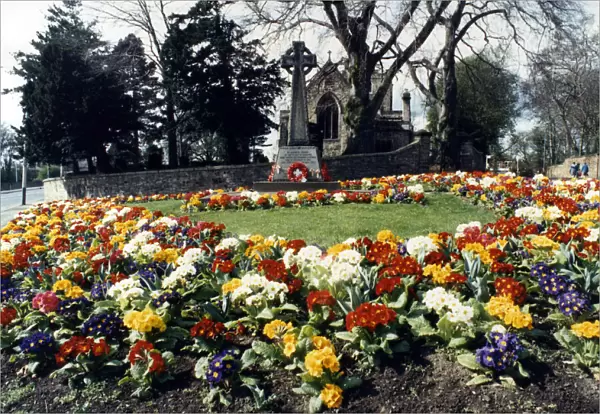 Spring flowers around a war memorial outside St Andrews church, Haughton