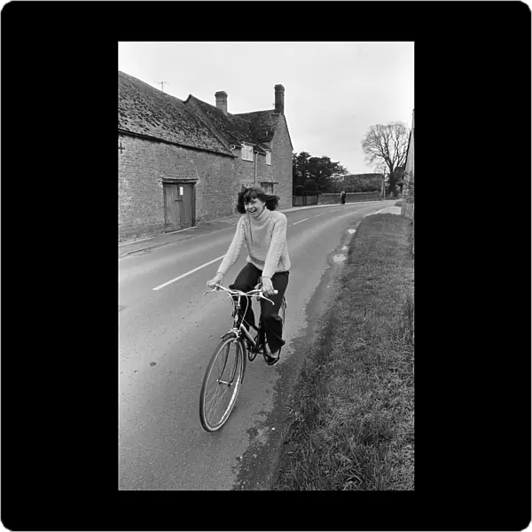 Pam Ayres riding her bicycle near her home in a village in Oxfordshire. 12th May 1977