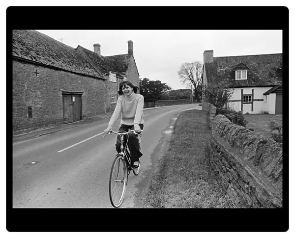 Pam Ayres riding her bicycle near her home in a village in Oxfordshire. 12th May 1977