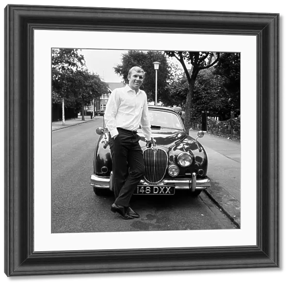 West Ham United captain Bobby Moore pictured standing beside his Jaguar car at home in