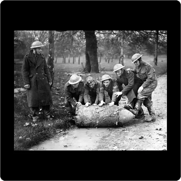 Members of a army bomb disposal squad rolling a unexploded German bomb through a London