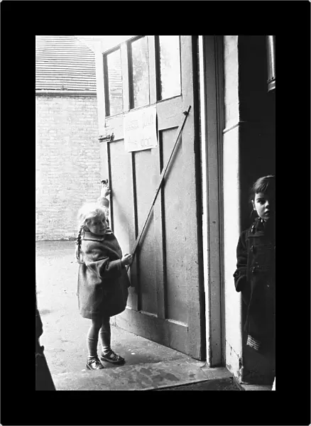 Child closing the door to the classroom following morning break at Roxeth Primary School