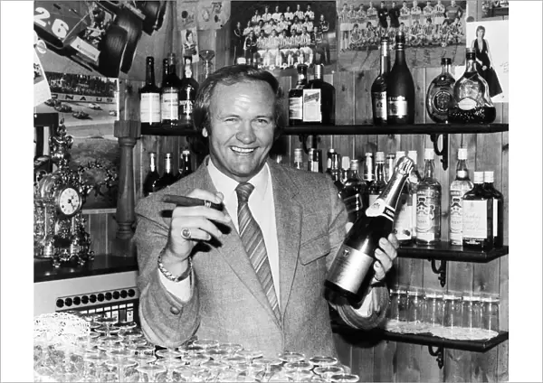New Manchester United football manager Ron Atkinson holds up a bottle of champagne in one