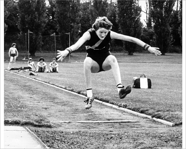 Melanie Moore throws her arms wide and bids for height and length in her long jump