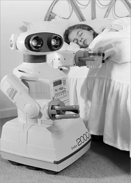 A young girl in bed being woken by an Omnibot 2000 toy robot. 21st October 1986
