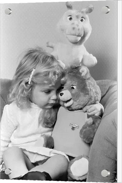 A young girl with soft toys, sitting next to a Teddy Ruxpin toy. 21st October 1986
