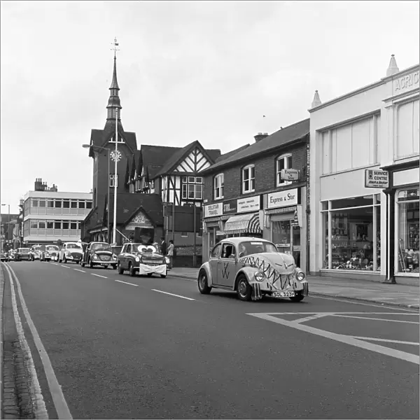 A parade of cars led by a decorated VW Beetle drive along Bridge Street, Stafford