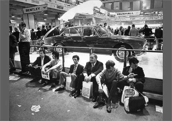 The Earls Court Motor Show. London Visitors sit on the floor in front of the Jaguar
