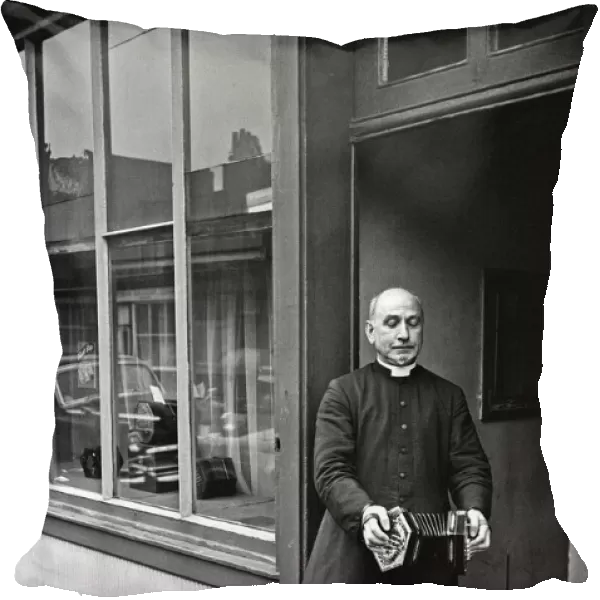 A priest plays a concertina outside Crabbs Concertina Shop in Liverpool Street
