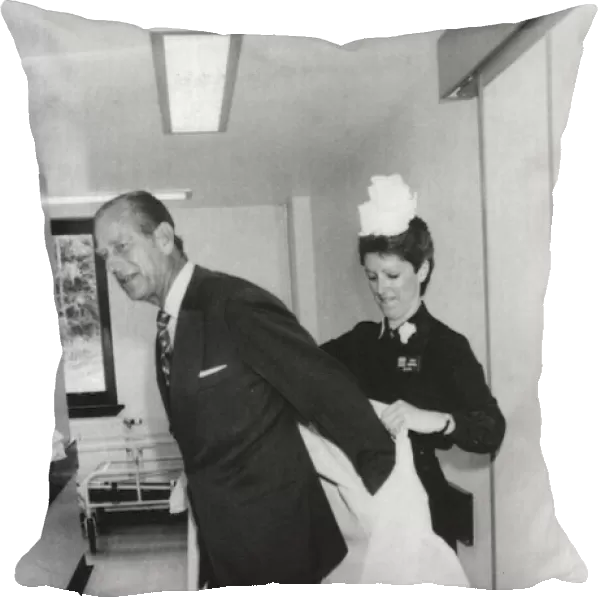The Duke of Edinburgh. Prince Philip being helped with his protective clothing by Matron