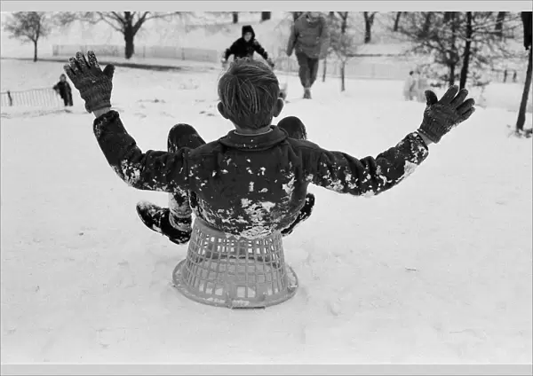 A boy sledging on a clothes basket in Greenwich Park, London, 27th December 1970