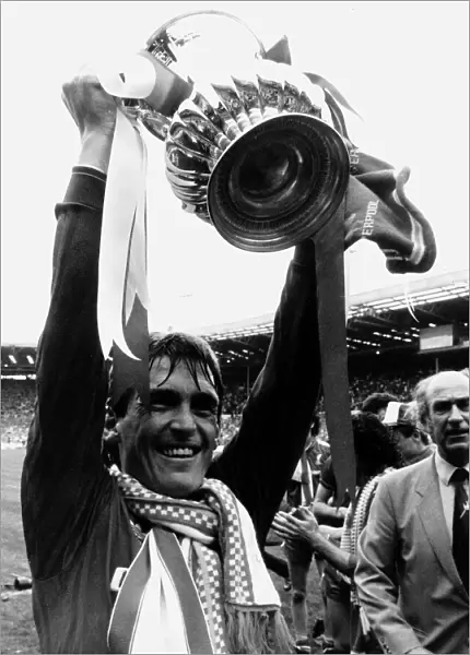 Liverpool player manager Kenny Dalglish holding the trophy aloft after their win against