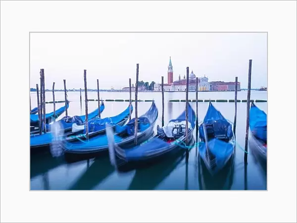 Serene landscape with clear sunrise sky on piazza San Marco in Venice. Row of gondolas parked on city pier