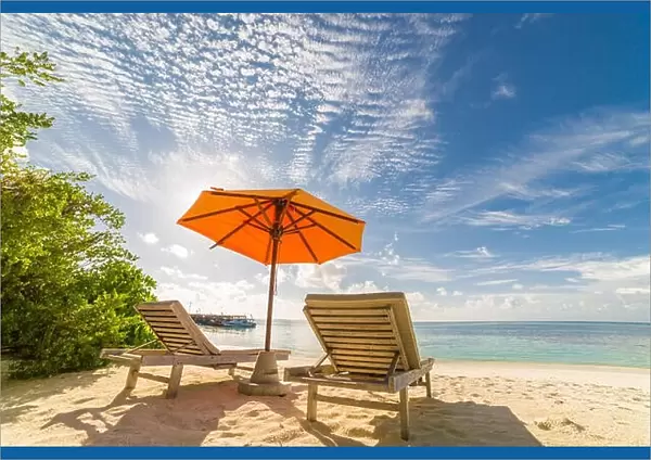 Two lounges or sun beds with umbrella on sunny beach. Summer landscape with sea view and mangrove. Tropical island