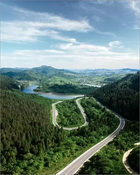 Flight over the summer mountains with mountain road serpentine, river and forest. Ukraine, Carpathian mountains. Landscape photography