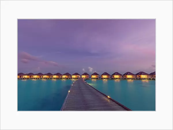 Maldives island sunset. Water bungalows resort at islands beach. Indian Ocean, Maldives. Beautiful sunset landscape, luxury resort and colorful sky