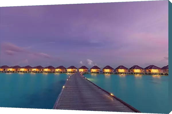 Maldives island sunset. Water bungalows resort at islands beach. Indian Ocean, Maldives. Beautiful sunset landscape, luxury resort and colorful sky