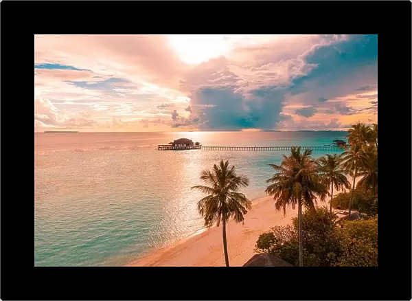 Aerial sunrise sunset beach bay view, colorful sky and clouds, wooden jetty over water bungalow. Meditation relaxation tropical drone view, sea ocean