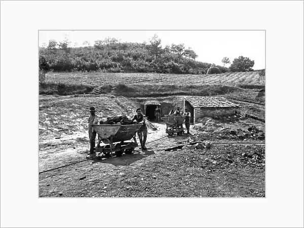 Group of miners shown pushing full carts on rails. The photograph was taken outside the Moriani di Follonica mine