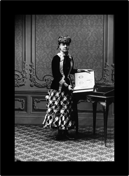 Portrait of a young woman in nineteenth century costume, looking through a photograph album
