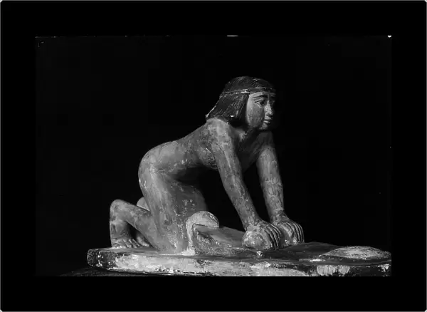 Egyptian sculpture in wood of a kneeling woman grinding wheat. Museo Archeologico, Florence