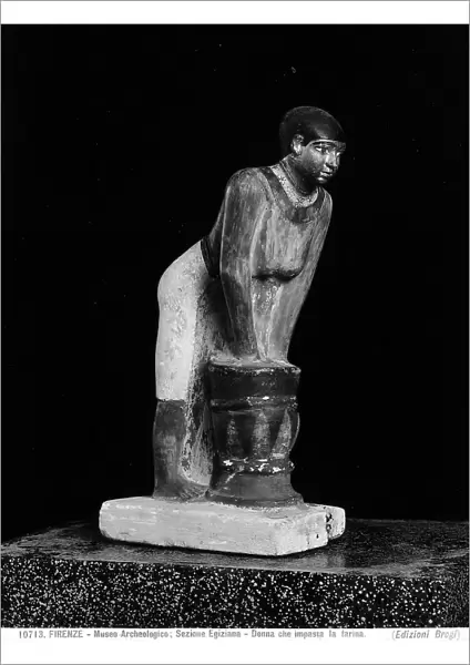 Egyptian sculpture in wood of a woman kneading flour. The Archaeological Museum, Florence